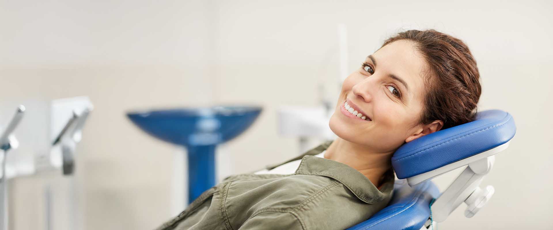 A woman sitting in a dental chair with a smile on her face.