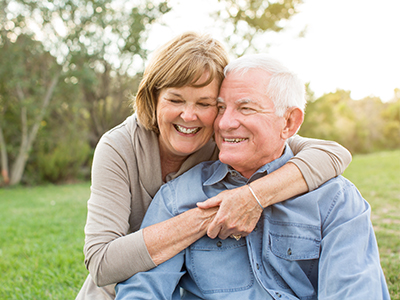 A man and woman are embracing each other outdoors during daylight hours.